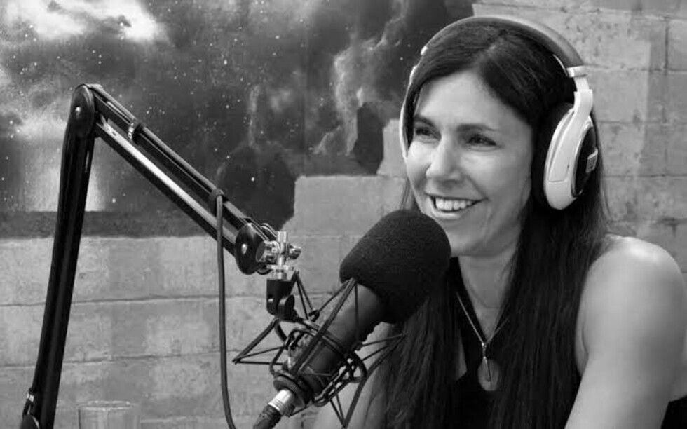 Lisa Tamati at the microphone in the podcast studio, wearing headphones