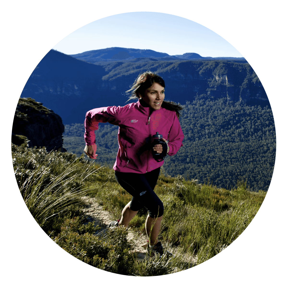 Lisa Tamati trail running in the hills, wearing a pink jacket