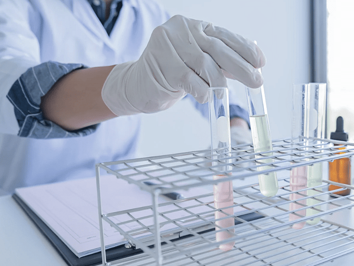 Gloved hand holding a test tube in a laboratory